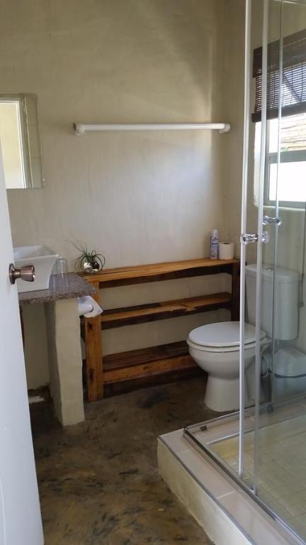 a bathroom with a toilet and a glass shower at Occi Lodge in Sodwana Bay