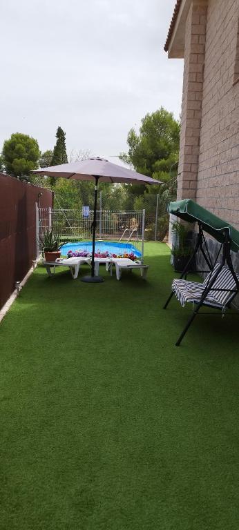 a patio with a table and an umbrella and a chair at La Casa del Cerezo in Nambroca