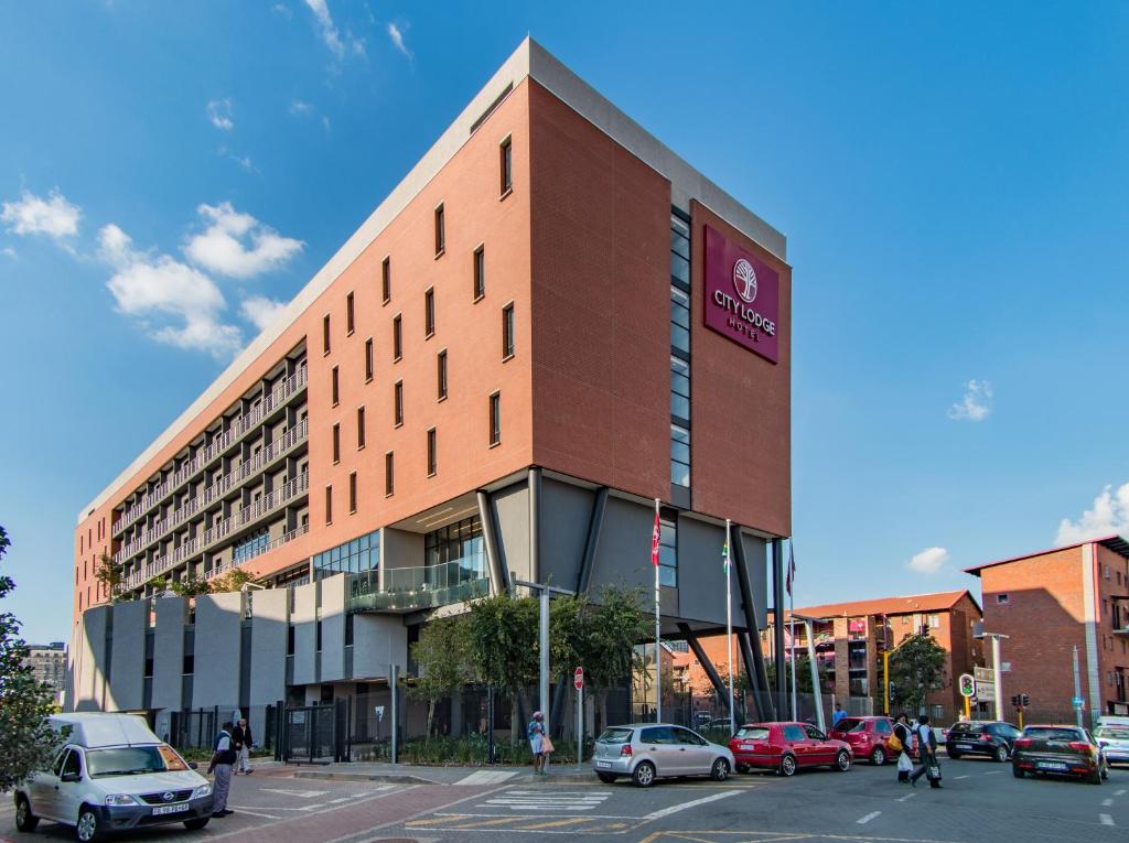 City Lodge Newtown, Johannesburg في جوهانسبرغ: مبنى كبير به سيارات تقف في موقف للسيارات