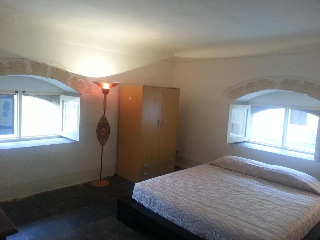 ein Schlafzimmer mit einem Bett und zwei Fenstern in der Unterkunft Il Posto Ideale in Vittoria