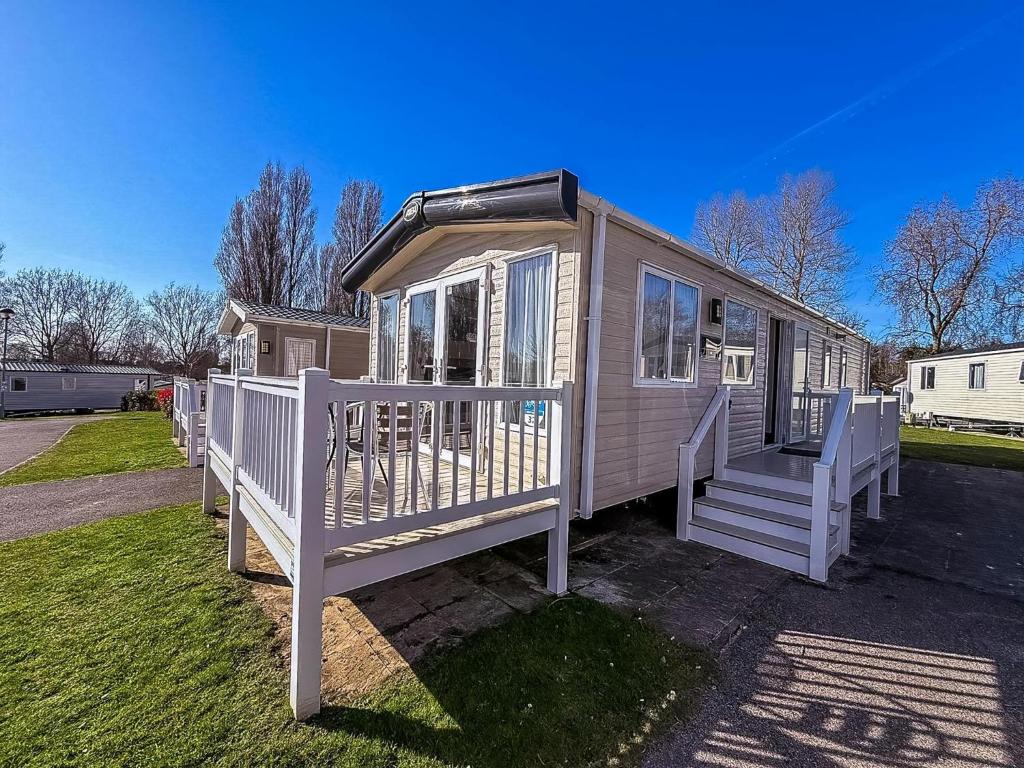 een klein huisje met een witte veranda en trap bij Modern Caravan With Decking At Haven Hopton-On-Sea Ref 80032M in Great Yarmouth