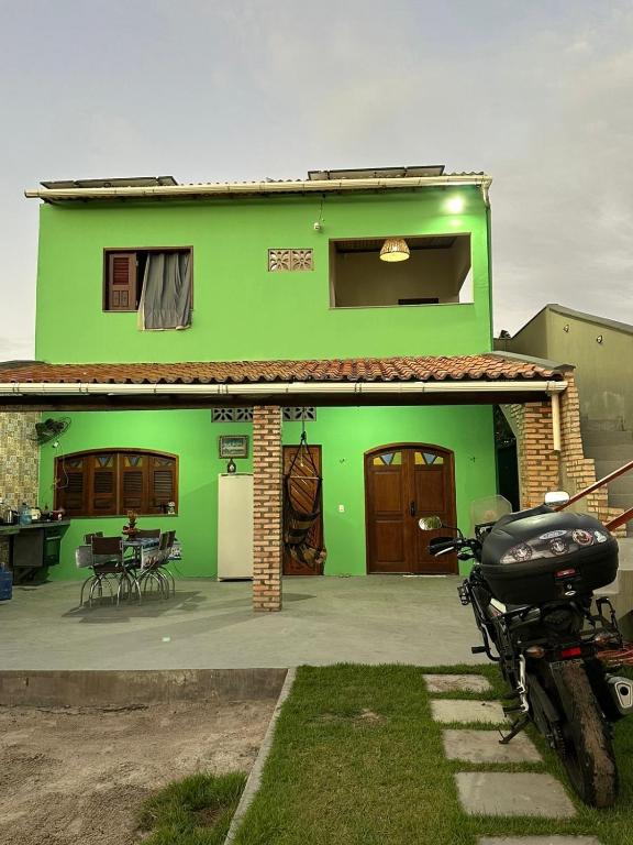 a green house with a motorcycle parked in front of it at Casa do Bento - Lençóis Maranheses in Santo Amaro