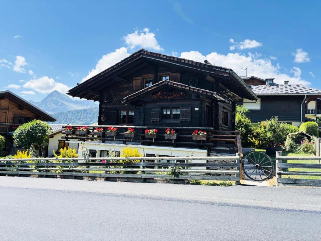 une petite maison avec des fleurs devant elle dans l'établissement Résidence Tavaillon - Chalet savoyard cosy centre village MAE-5161, à Notre-Dame-de-Bellecombe