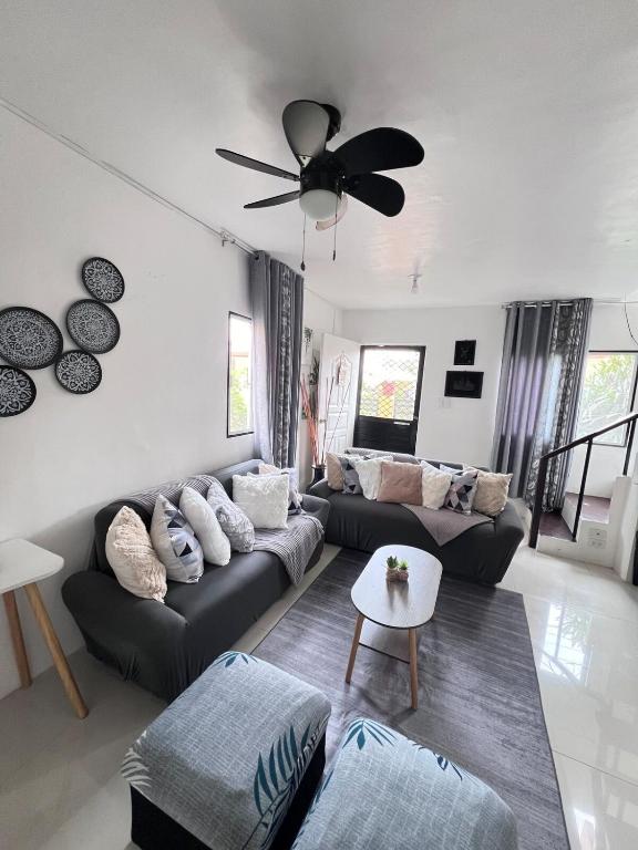 a living room with two couches and a ceiling fan at Musky in Gray in Ozamis