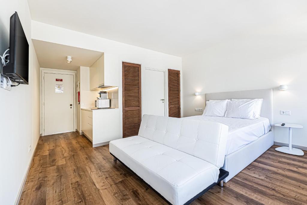 ein weißes Bett und ein Sofa in einem Zimmer in der Unterkunft salgado`s nest in Portimão