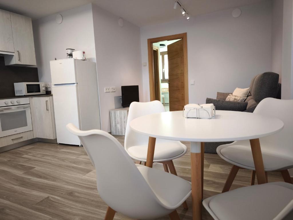 Una cocina y una sala de estar con una mesa y sillas blancas. en Apartamentos Villa de Panes - San Roque, en Panes