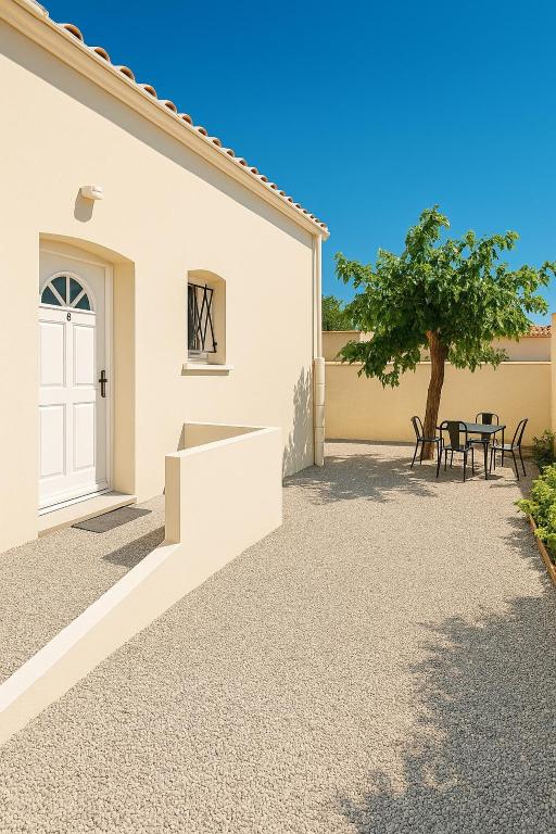 une allée avec une porte blanche, une table et un arbre dans l'établissement Le numéro 3, à Mirepeisset