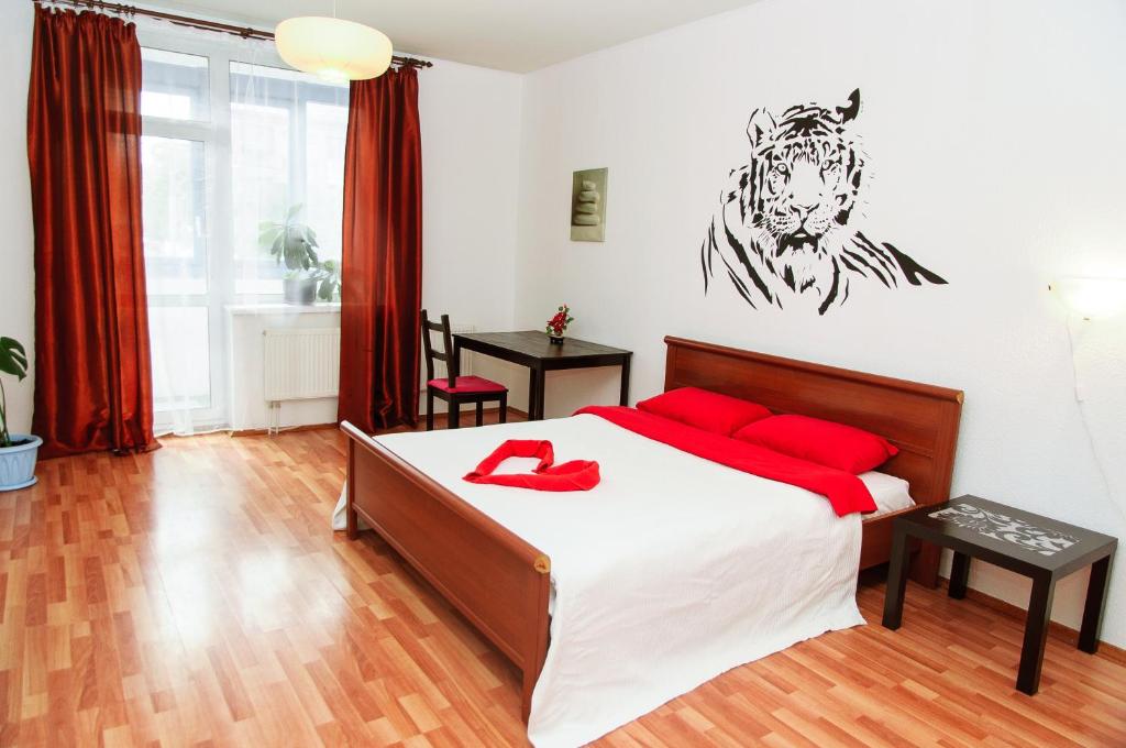 a bedroom with a bed with red pillows and a tiger on the wall at Yin Yang in Moskva Complex in Yekaterinburg