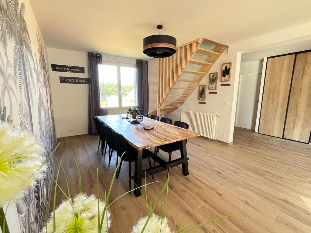 a dining room with a wooden table and stairs at La maison de Louise in Sizun