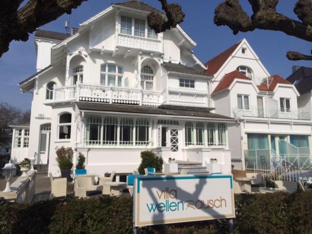 ein weißes Haus mit einem Schild davor in der Unterkunft Villa WellenRausch - Adults Only in Travemünde