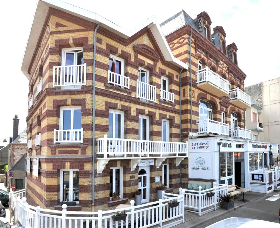 un grand bâtiment en briques avec des balcons blancs dans une rue dans l'établissement Hotel Le Rayon Vert, à Étretat