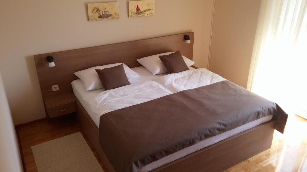 a bedroom with a bed with white sheets and brown pillows at Rooms Vukušić in Rab