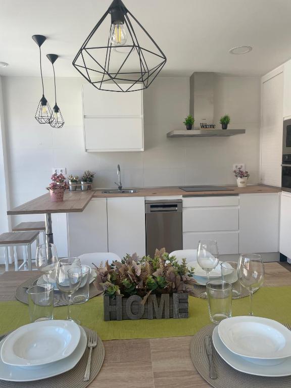 a kitchen with a table with plates and wine glasses at Apartamentos AriNai climatizado y con garaje in Los Arcos