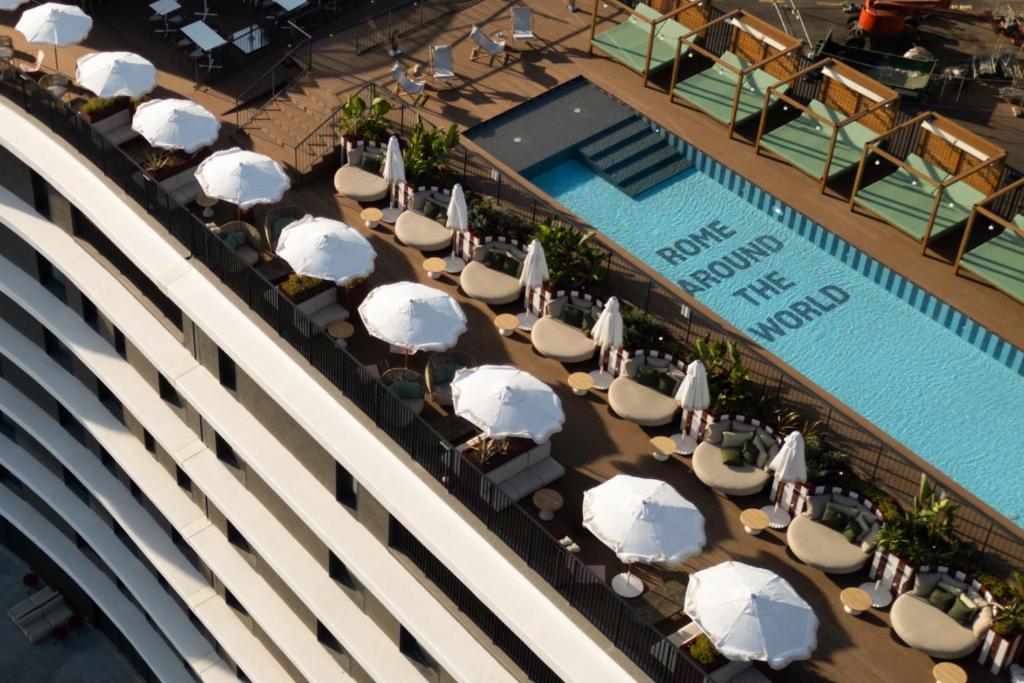 eine Draufsicht auf einen Pool mit Stühlen und Sonnenschirmen in der Unterkunft The Social Hub Rome Extended Stay in Rom
