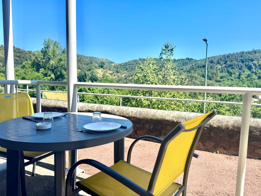 a table and chairs on a balcony with a view at La Vallée Appartement 30 - Thermes Neyras les Bains in Meyras