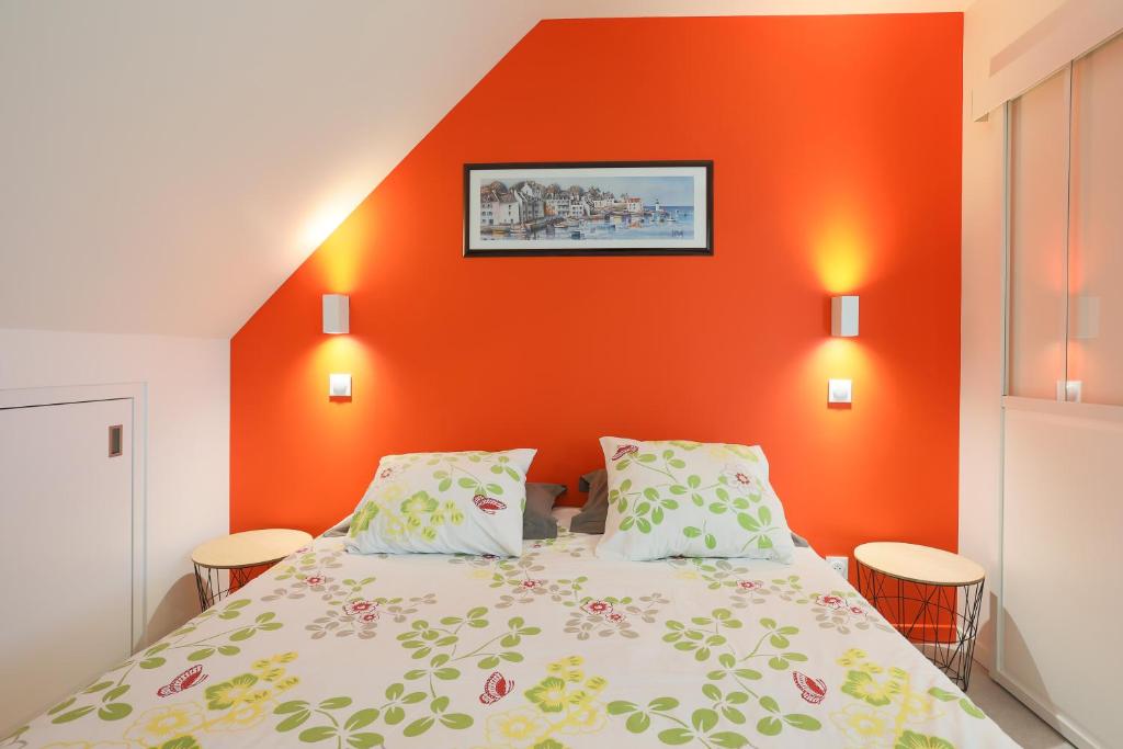 a bedroom with a bed with an orange wall at Gîte Kerli cosy 2kms plage in Trévou-Tréguignec