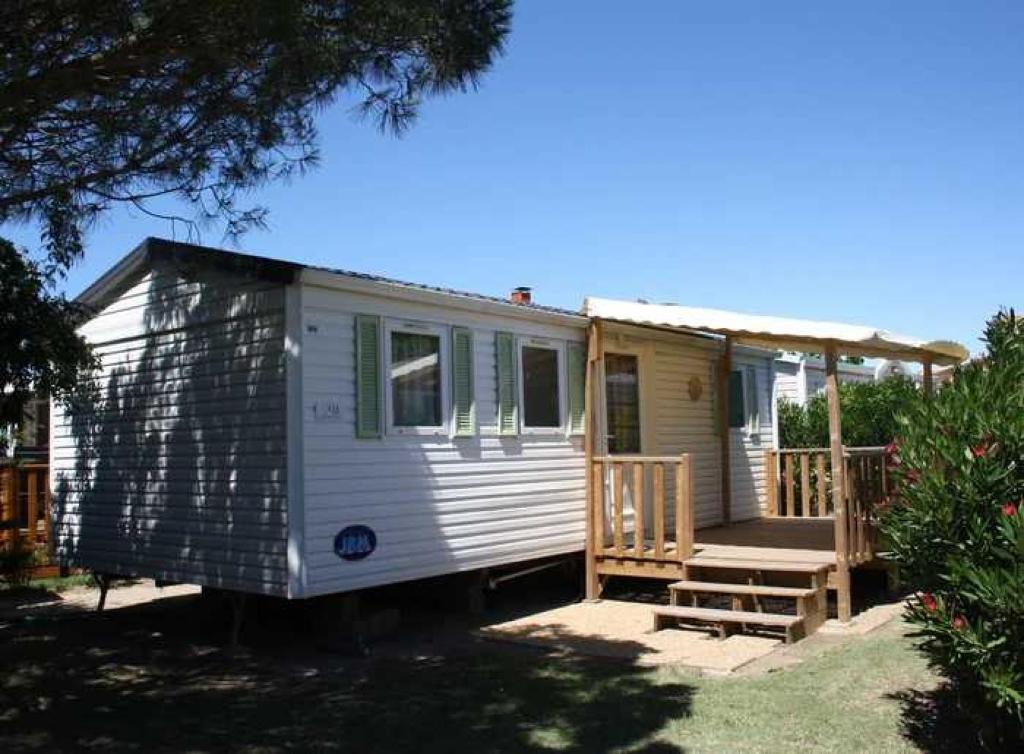 une petite maison blanche avec une terrasse couverte et une terrasse dans l'établissement Camping 4 étoiles - Piscine - ccbbehe, à Saint-Cyprien