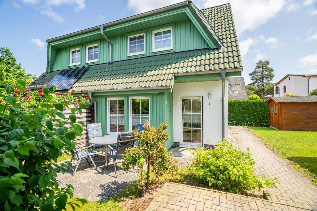 a green house with a table and chairs at Ferienhaus Knospe in Ueckeritz