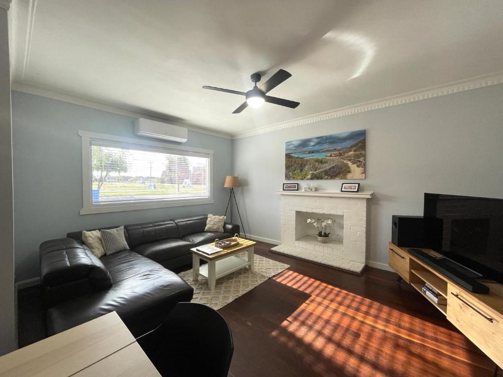 a living room with a black leather couch and a fireplace at Dempster House in Esperance
