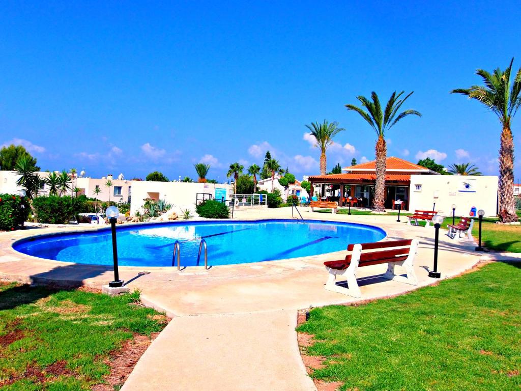 a swimming pool with a bench and palm trees at Coral Bay Apartment - Prime Tourist Location in Coral Bay