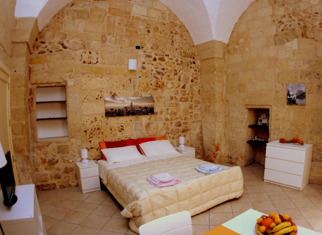 een slaapkamer met een bed en een stenen muur bij Casa Fortunato Corte Adorni in Lecce