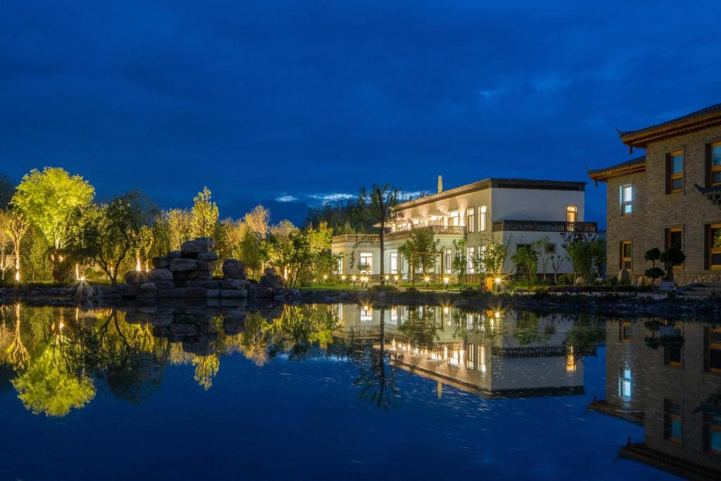 a building next to a lake at night at TOTOLO Winery Vacation Homestay in Yinchuan