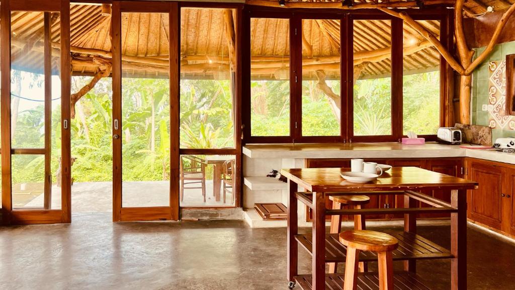 a kitchen with a wooden table and some chairs at Yoga bale house in Karangasem