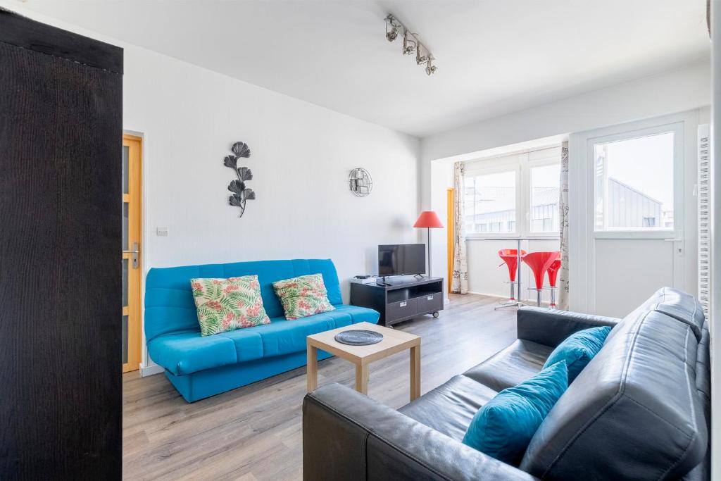 un salon avec un canapé bleu et une télévision dans l'établissement Soleil Couchant Balcon Parking Metz Gare Un-Séjour-à-Part, à Metz