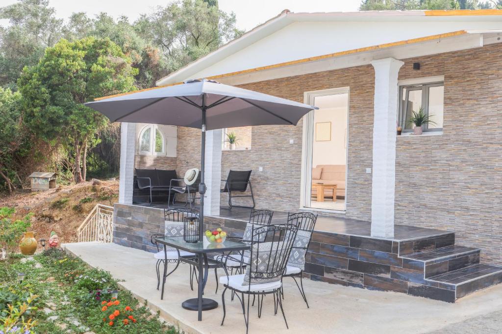 een tafel en stoelen met een parasol op een terras bij Rena's House, Viros, Corfu in Corfu