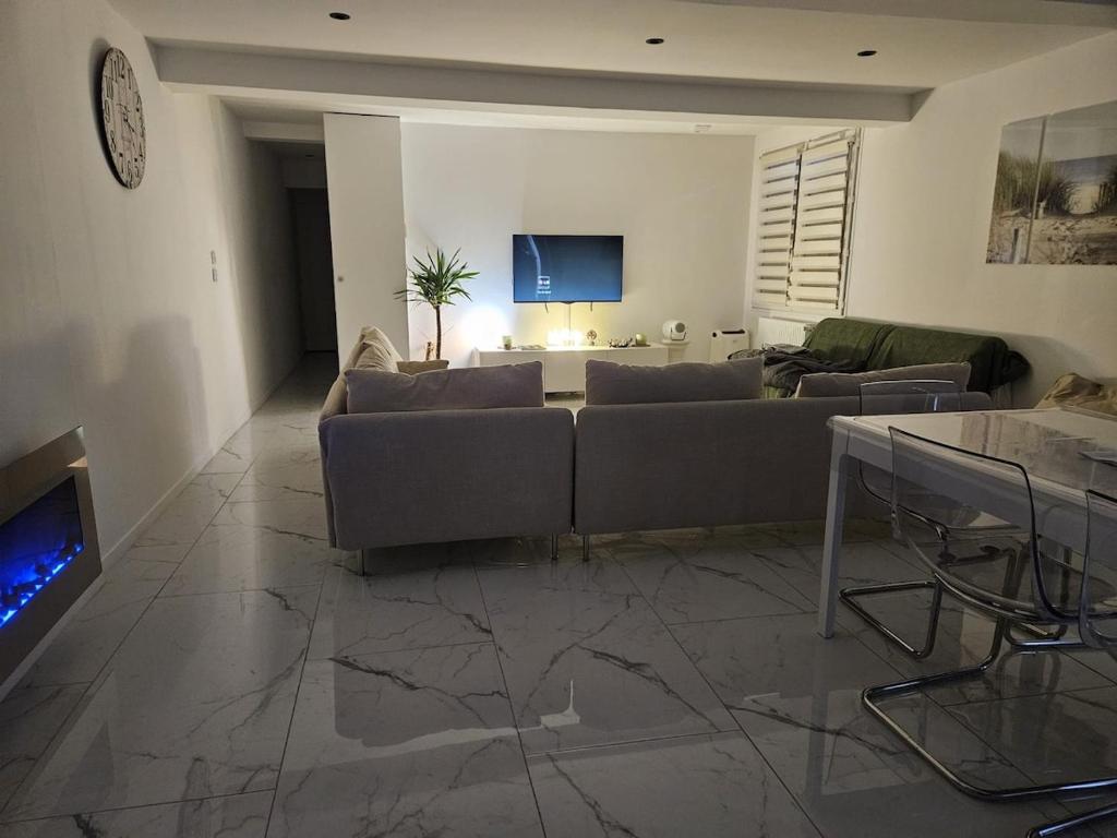 ein Wohnzimmer mit Sofa und Fernseher in der Unterkunft Maison dans corps de ferme Aéroport beauvais 14 minute 