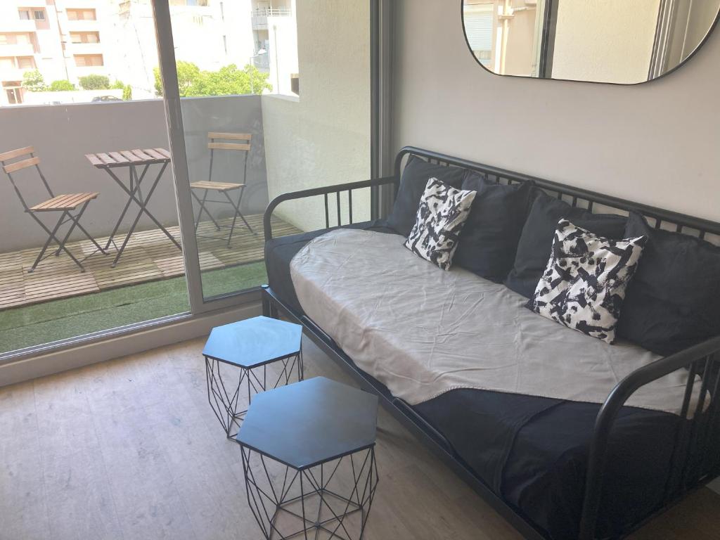 un canapé et deux tabourets dans une pièce avec balcon dans l'établissement La Venise du Languedoc Sète,Terrasse,mer,cosy, à Sète