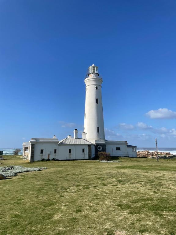 a lighthouse sitting on top of a grass field at SealPoint Studio in Cape St Francis