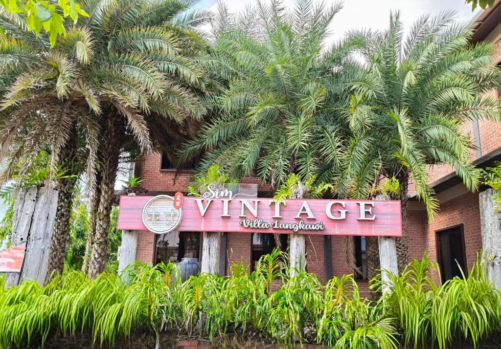 a sign for the entrance to a building with palm trees at Sim Vintage Villa Langkawi in Kuah