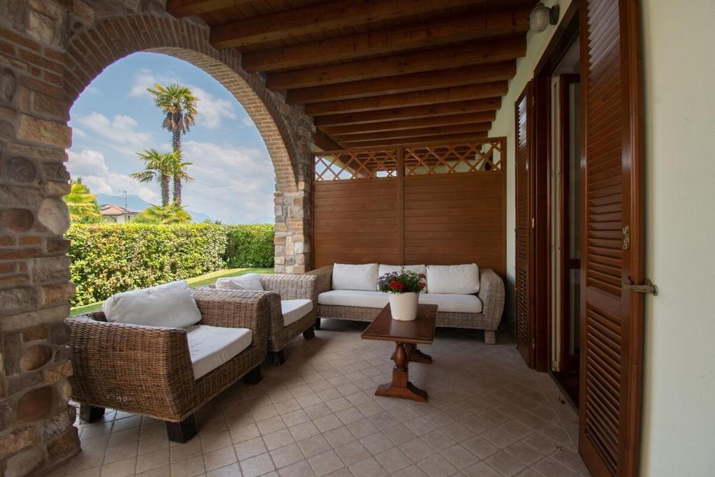 an outdoor patio with wicker chairs and a table at Tavaredo House in Polpenazze del Garda