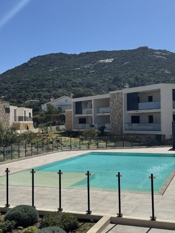 une grande piscine devant un immeuble dans l'établissement T2 dans résidence avec piscine, à Calvi