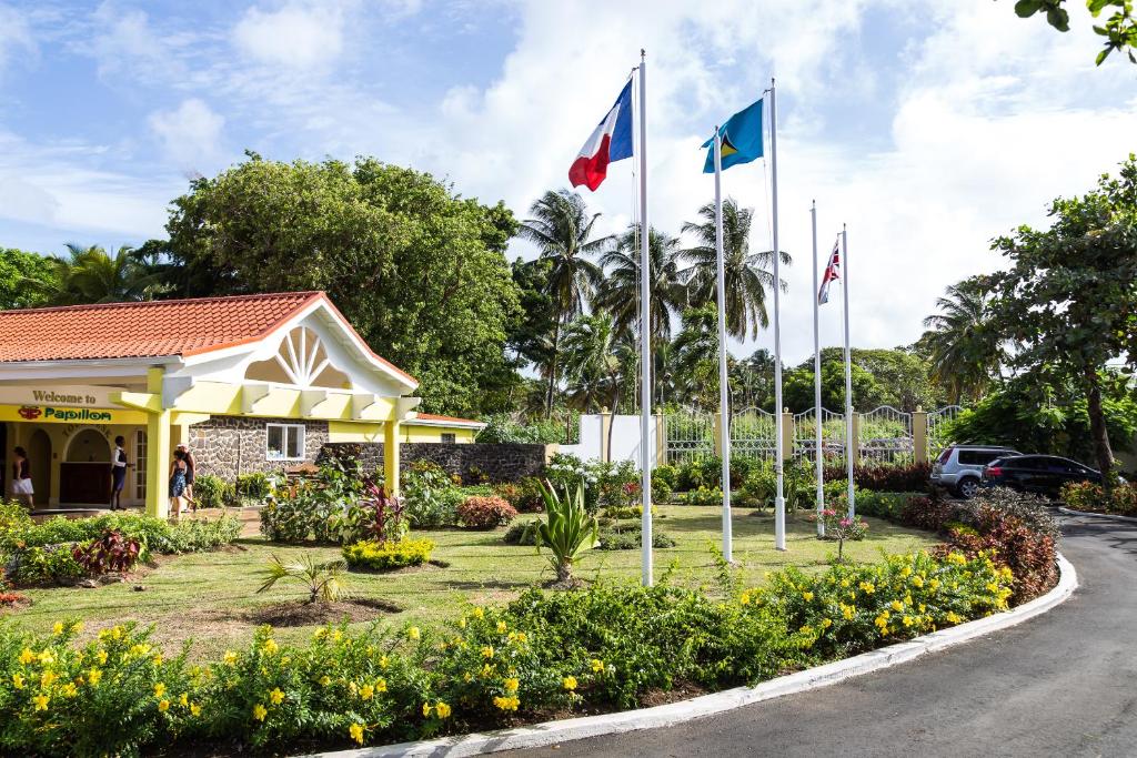 a building with flags in front of a garden at Starfish St Lucia - All Inclusive in Rodney Bay Village