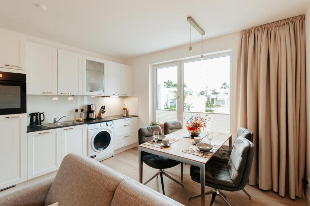eine Küche und ein Wohnzimmer mit Tisch und Stühlen in der Unterkunft Appartement Kranich - Moderne Ferienwohnung direkt am Schloss Ranzow! in Lohme