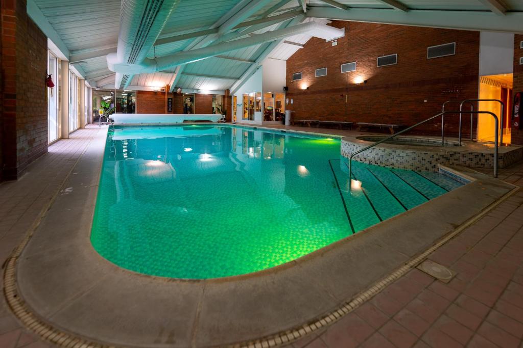 a large swimming pool with green water in a building at Orida Hotels Newbury in Newbury