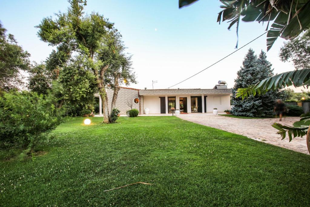 une maison avec une pelouse devant dans l'établissement Villa con parco e piscina, à San Michele Salentino
