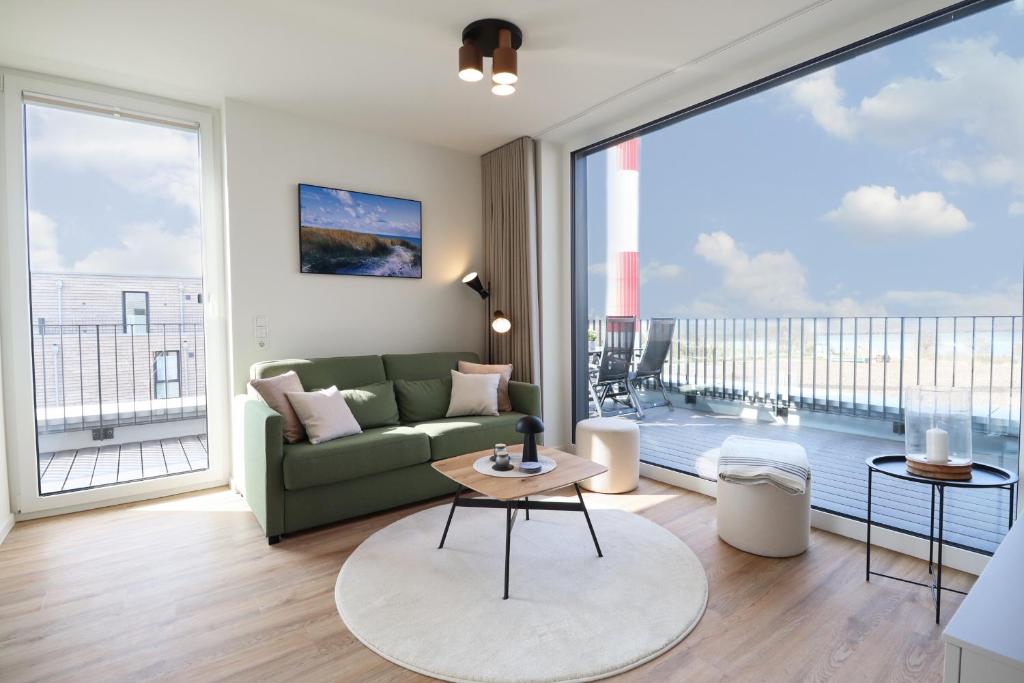 フェーマルンにあるBeltBlick 11 – Ferienwohnung mit unverbautem Meerblick & Dachterrasse!のリビングルーム(緑のソファ、大きな窓付)