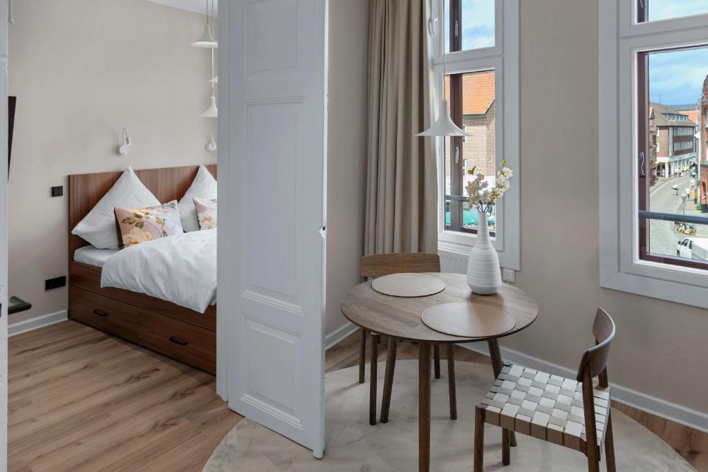 a small room with a bed and a table and a chair at Distillery Apartments in Lüneburg