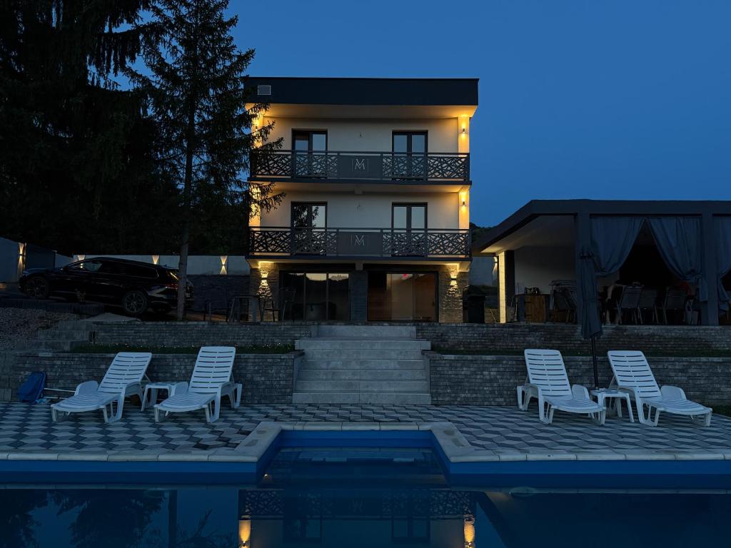 a house with chairs and a swimming pool at night at Vila Monti 