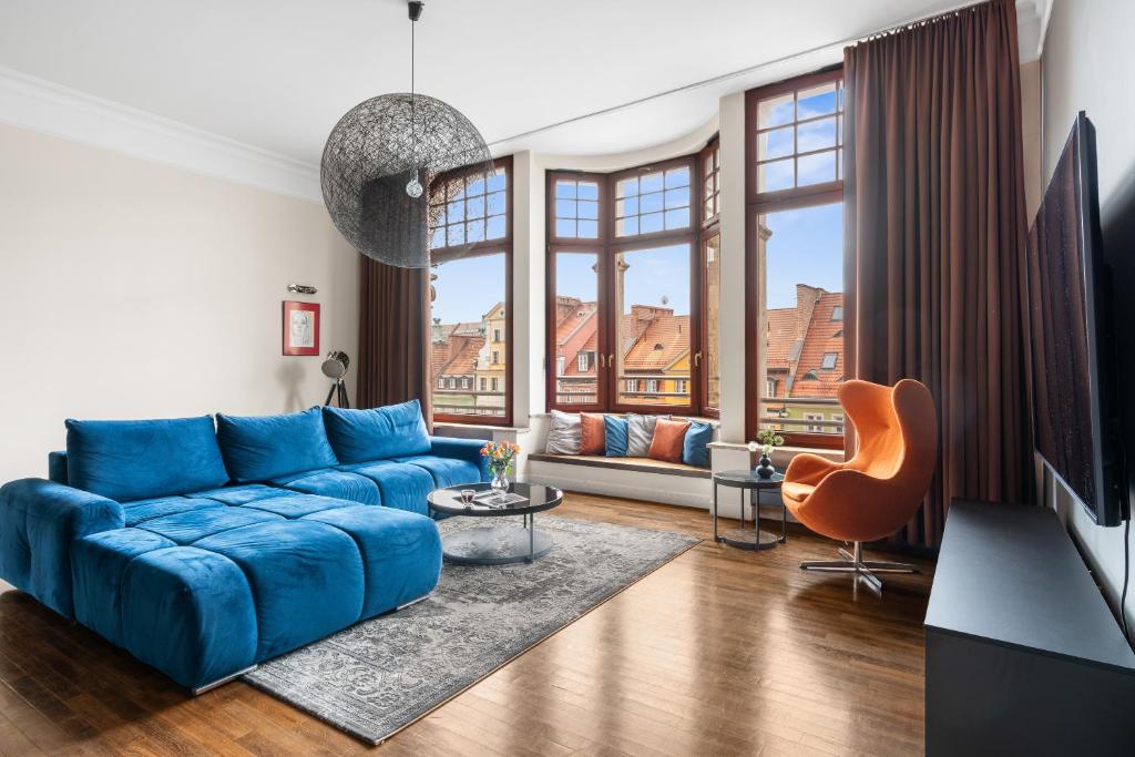 a living room with a blue couch and large windows at Majestic Residence -150m2 with Iconic Market Square View AS HOME Apartamenty R506 in Wrocław