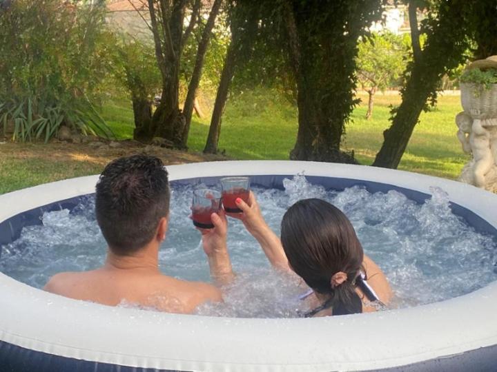 a man and woman in a jacuzzi tub with drinks at Magnolias Cottage with Jacuzzi and mountain view in Lousã