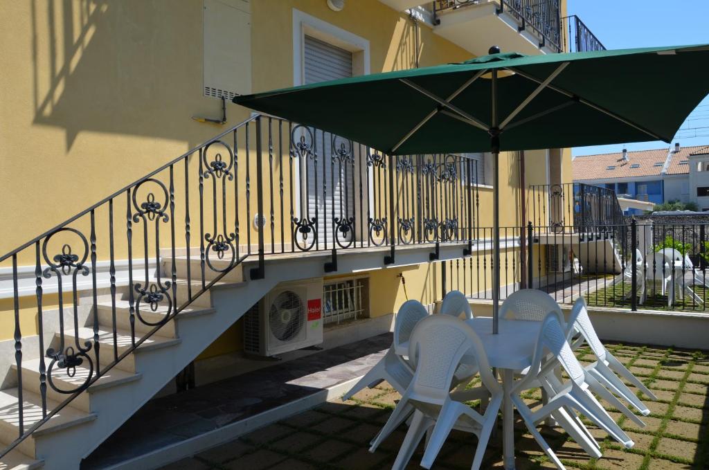 a table and chairs under an umbrella next to a staircase at Casa Vacanze CuprAmare in Cupra Marittima
