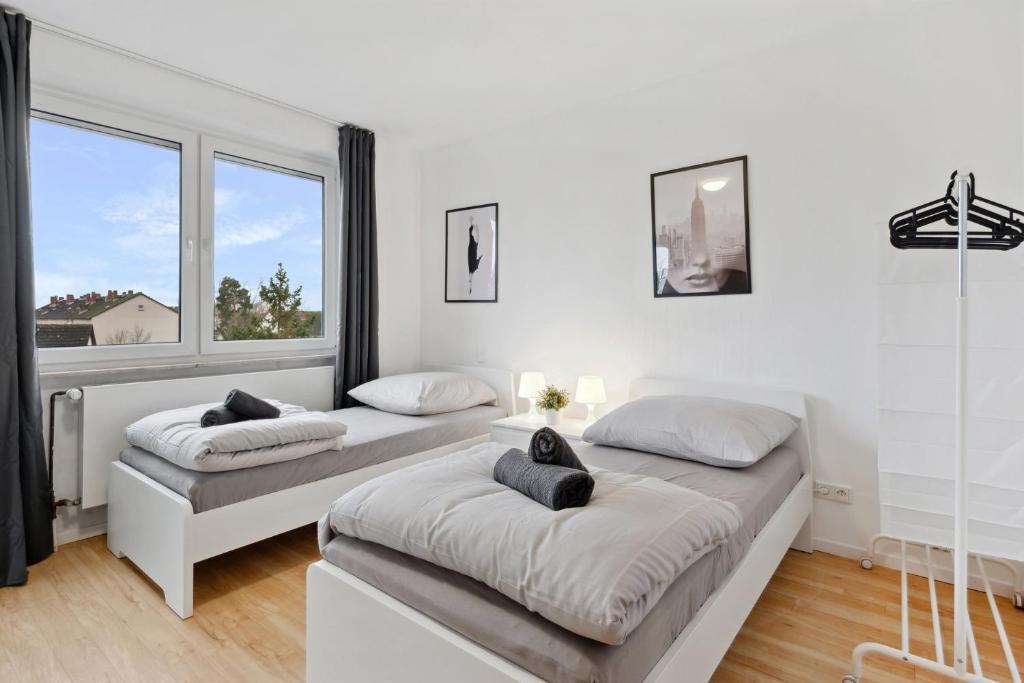 two beds in a white room with two windows at MONTEUR - Unterkunft für bis zu 5 Personen in 64546 Mörfelden-Walldorf - GG11 in Mörfelden-Walldorf