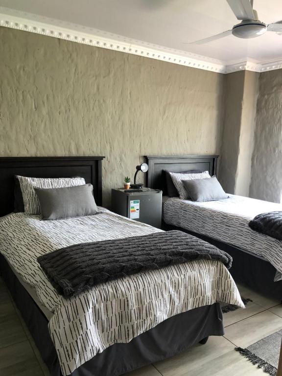 two beds sitting next to each other in a bedroom at Farmers Lodge in Piet Retief