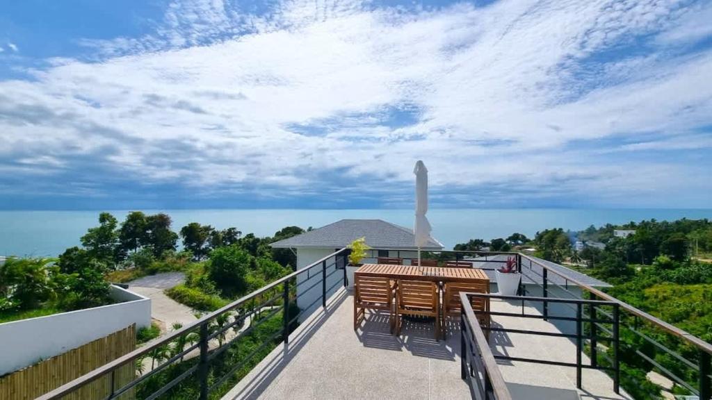 a balcony with a table and chairs and the ocean at Sunset villa rooftop with pool 180 Seaview in Koh Phangan