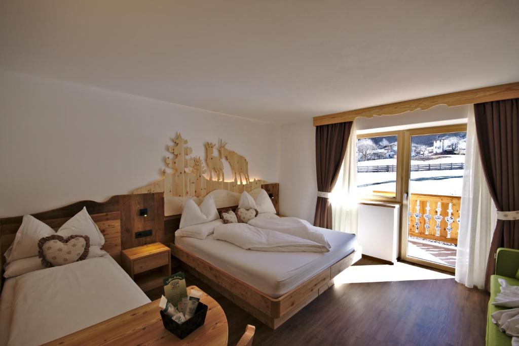 a bedroom with two beds and a large window at Agritur Maso Piasina in Tesero