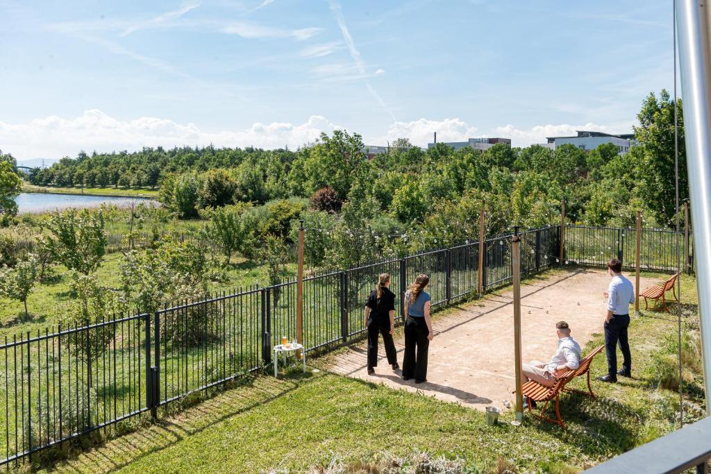 a group of people standing on a walkway next to a fence at DoubleTree by Hilton Lyon Eurexpo & Spa in Saint-Priest